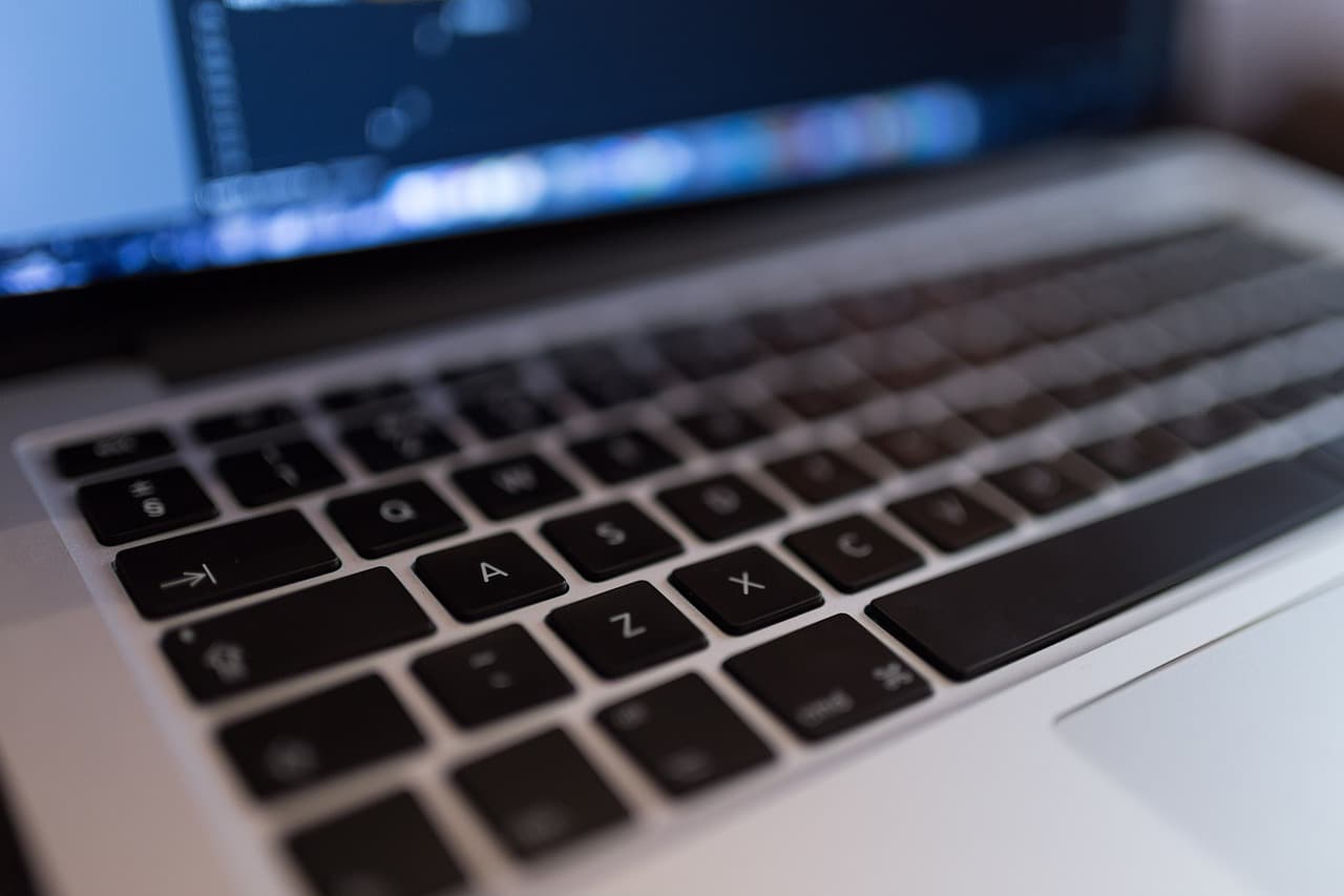 A silver Macbook laptop with black keys displaying a computer screen that has an application on it for programming and coding.