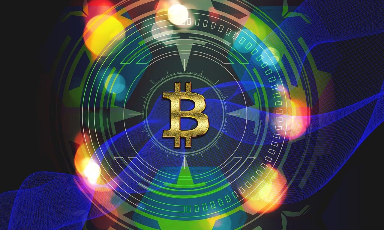 The bitcoin logo in the center of a digitally made circle in blue surrounded by multicolored lights and a blue background.
