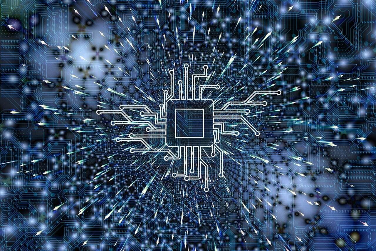 A square electronics chip with white lines coming out representing wires in front of a blue image with a lot of lines on it.