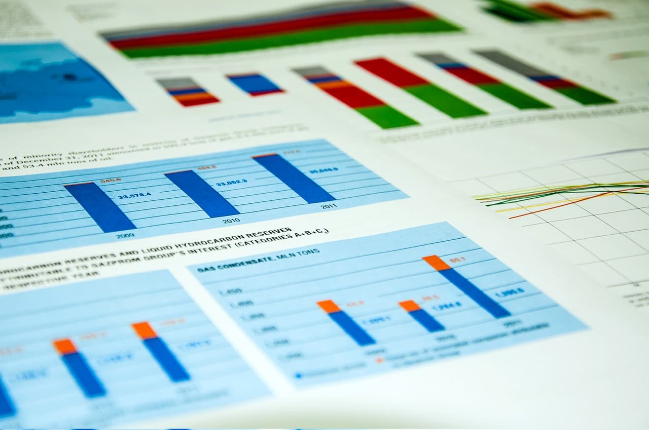 A piece of paper with multiple bar charts on it colored mainly in blue with multiple secondary colors as well as black numbers.