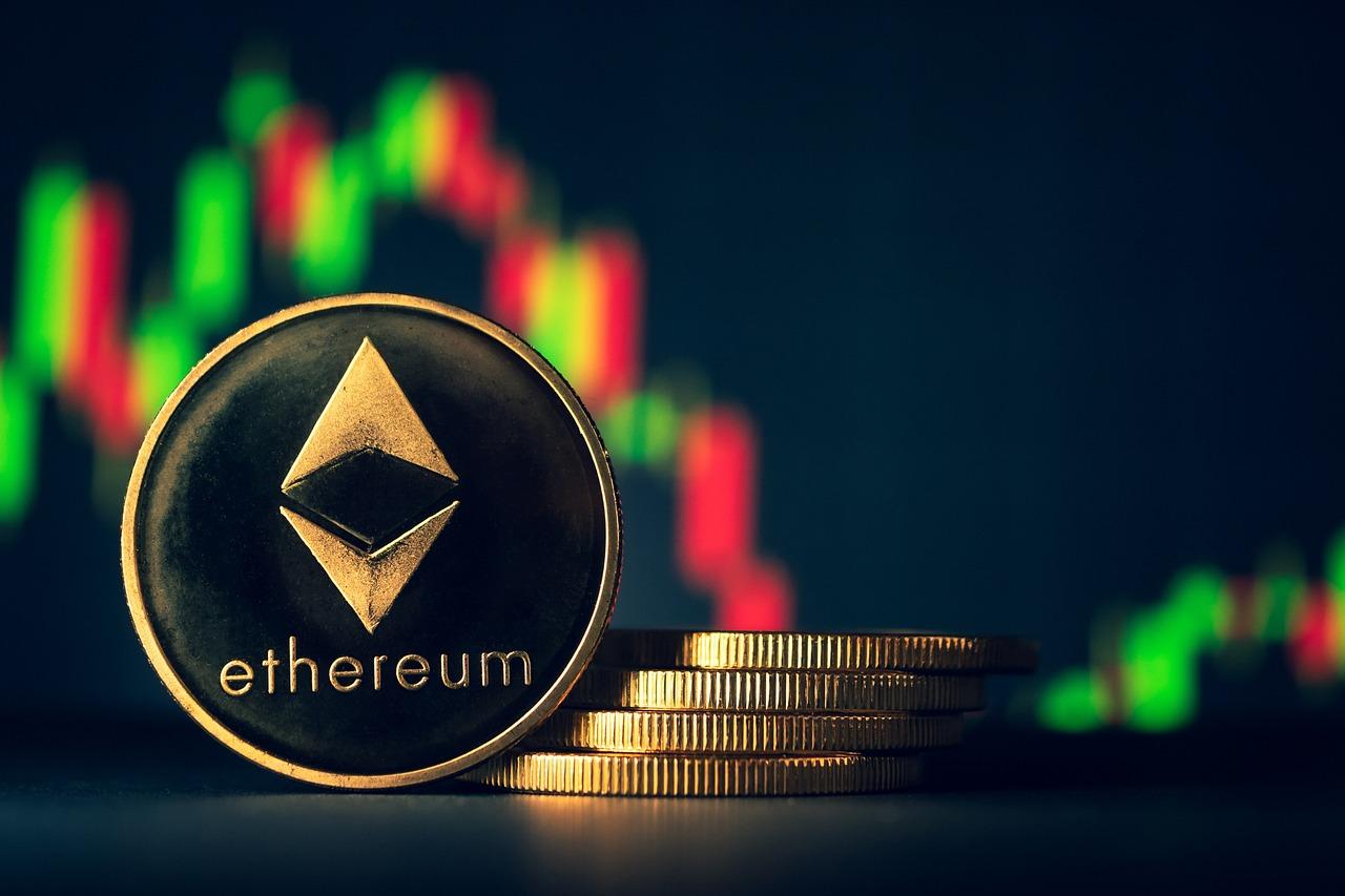 A golden coin with the Ethereum logo on it in black next to a pile of four other coins and a crypto market chart behind them.