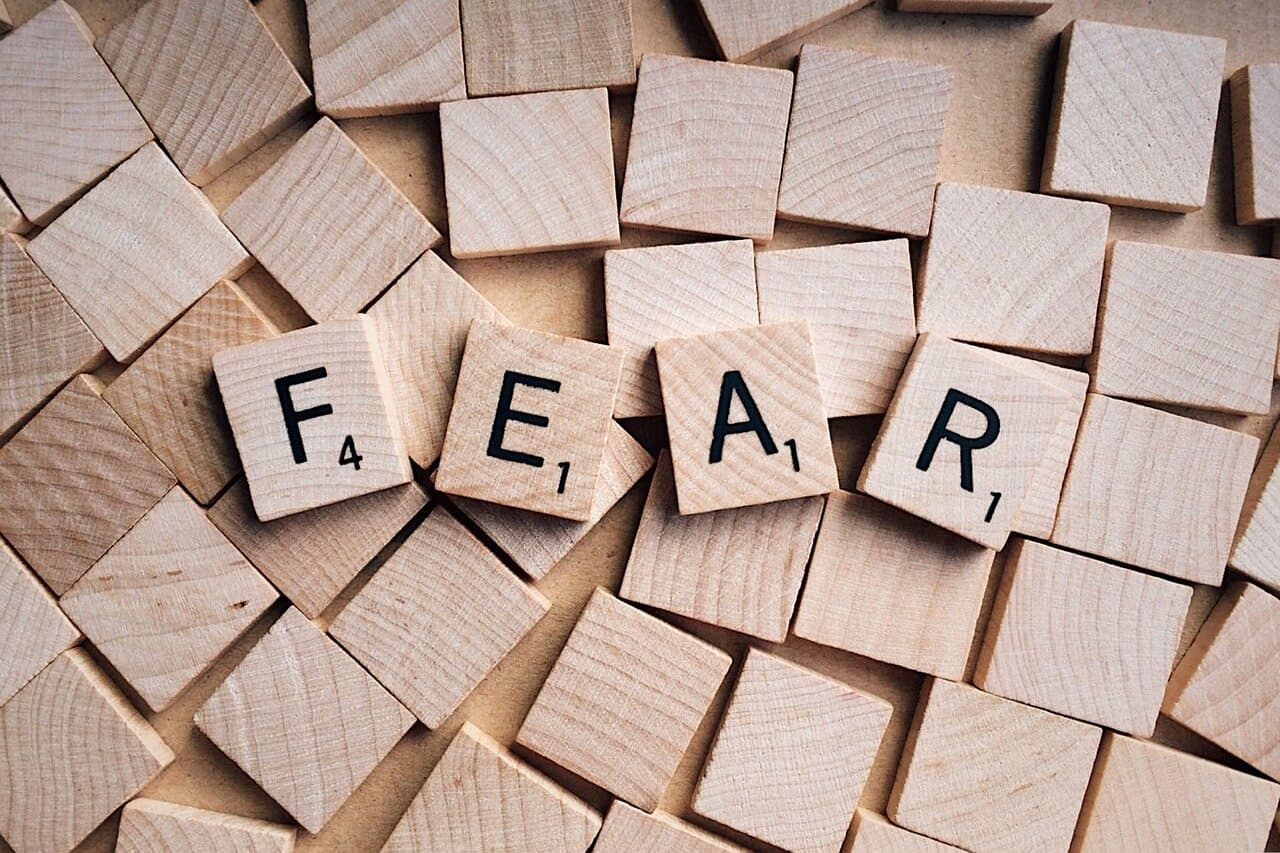 The word fear is written out in black letters on individual wooden squares resting on top of a pile of more wooden squares.