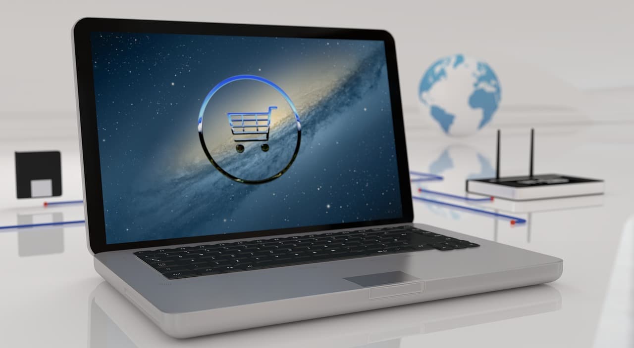 A silver Apple Macbook laptop showing an image of space colored blue with a grey and light blue shopping cart logo on top of it.