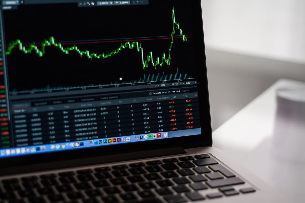 A laptop computer screen with a crypto candle chart showed on it in green and white with the chart going up and down evenly.