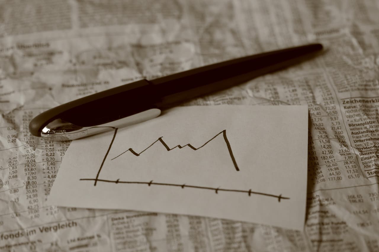 A white piece of paper with a chart written on it that goes up and down with the final movement down next to a dark brown pen.