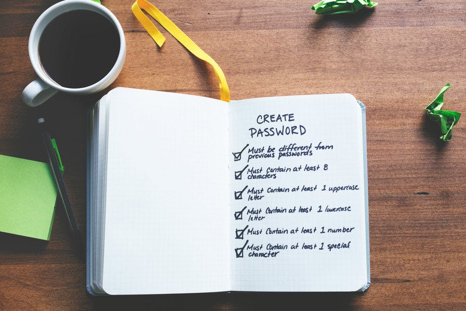 A long checklist written inside of a white notebook on a wooden desk next to a full cup of coffee and a mechanical pencil.