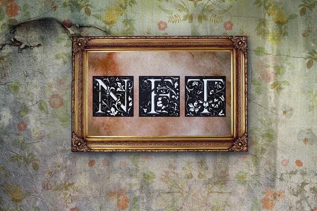 A brown picture frame with 3 white letters inside spelling NFT having black colors around them on plant-themed wallpaper.